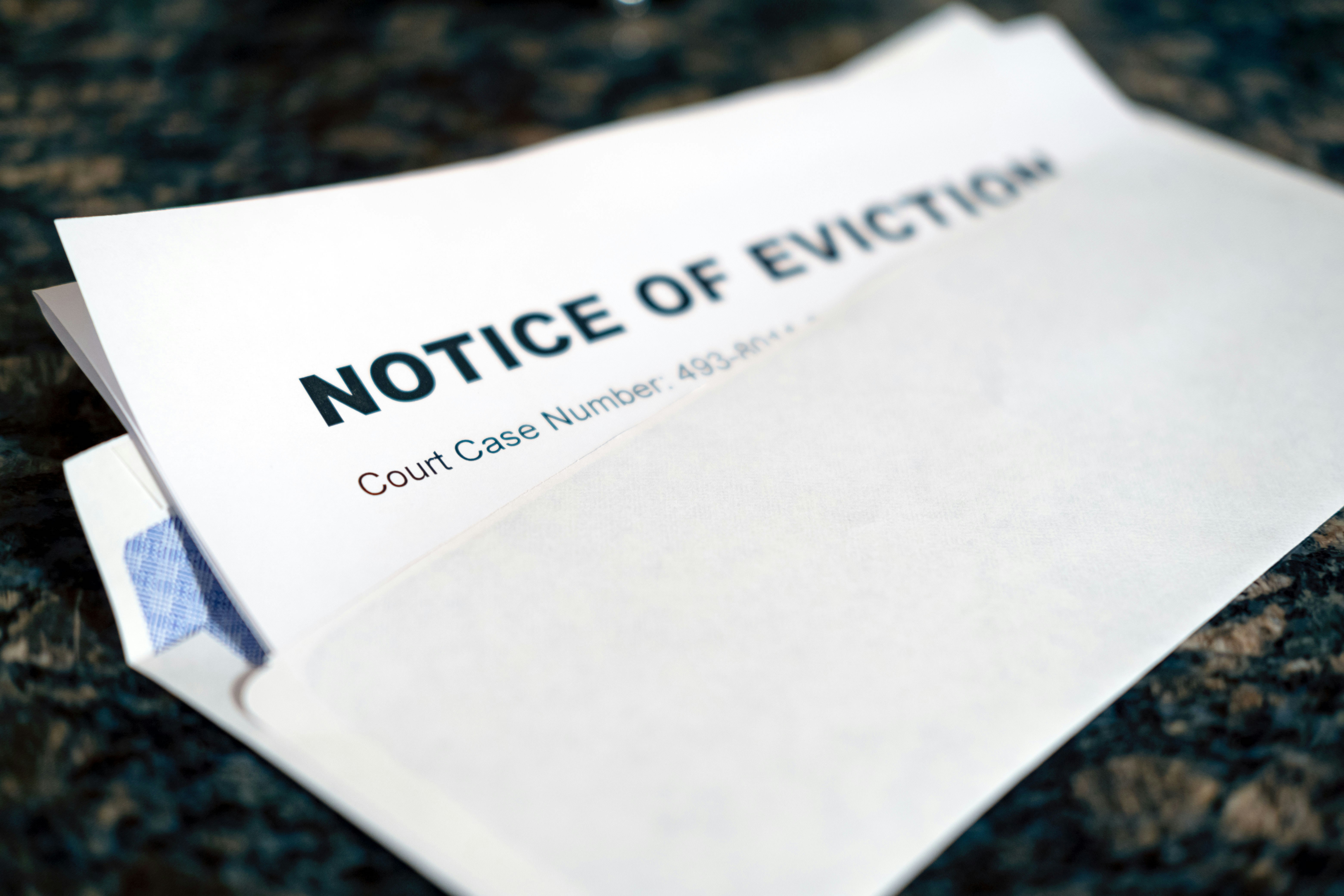 Photo by Allan Vega on Unsplash of a notice of eviction coming out of an envelope
